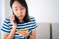 Confused portraitÃÂ young woman holding credit cards having problem online payment with credit card making rejected unsecure online Royalty Free Stock Photo